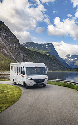 Camping-car intégral Pilote roulant sur une route le long d'un lac de montagne.