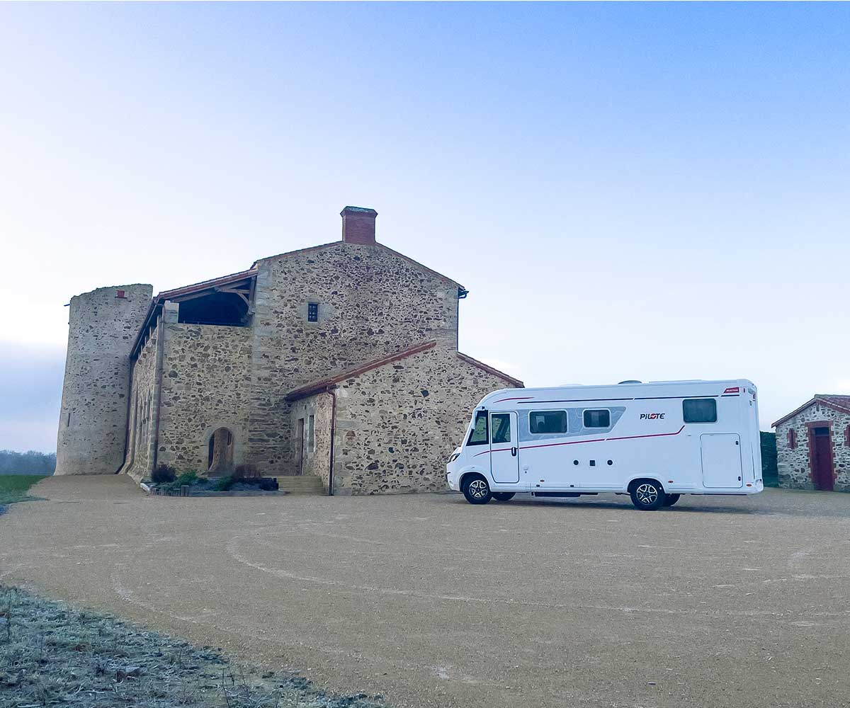 Camping-car intégral G720FGJ Sélection Pilote vu de l'extérieur, de côté, à côté d'un château.