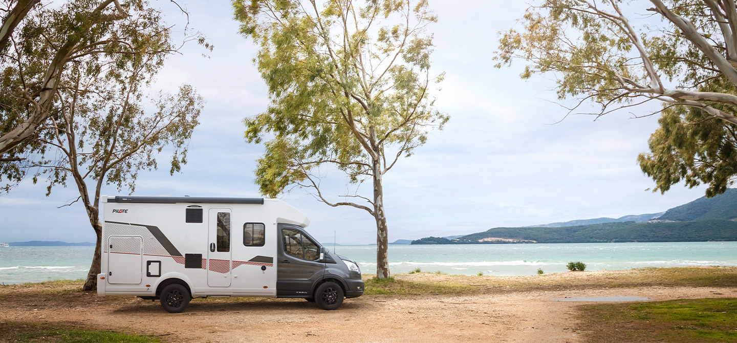 Camping-car profilé étroit Pilote à l'arrêt sur un chemin de terre au bord de la mer.