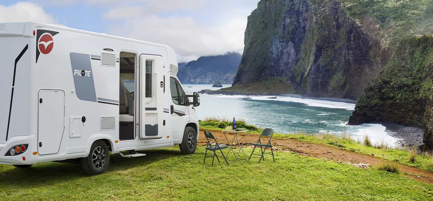 Camping-car profilé Pilote à l'arrêt pour la nuit, au bord d'une falaise donnant sur la mer.