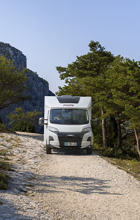 Camping-car profilé Pilote roulant sur un chemin de cailloux.