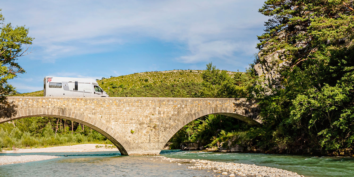 Camping-car profilé Pilote roulant sur un pont enjambant un cours d'eau.